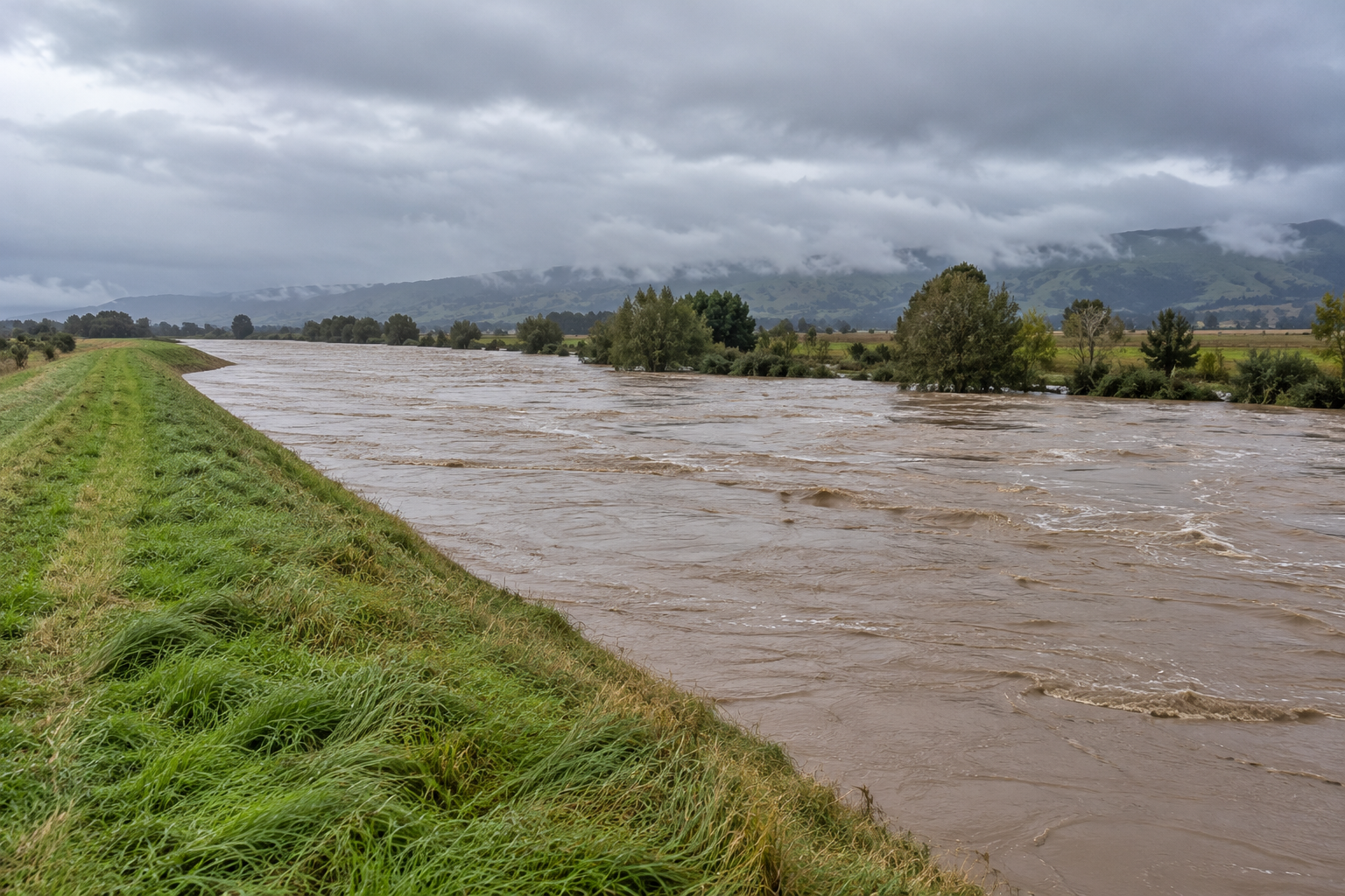 A swollen river beneath misty hills